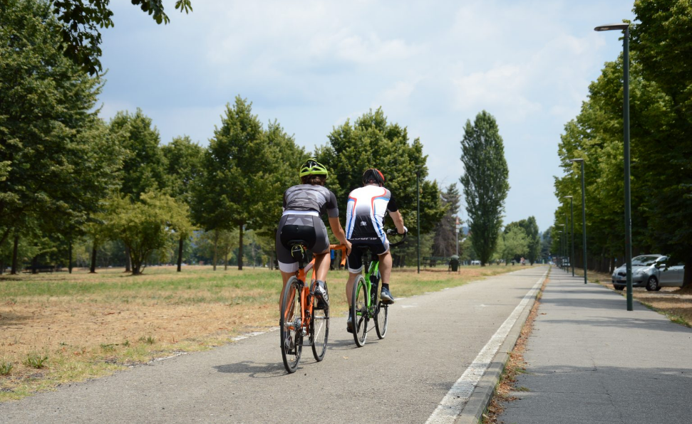 Due bici da strada arancone e verde di Boeris Bikes Torino, guidata da due ciclisti di spalle su una pista ciclabile